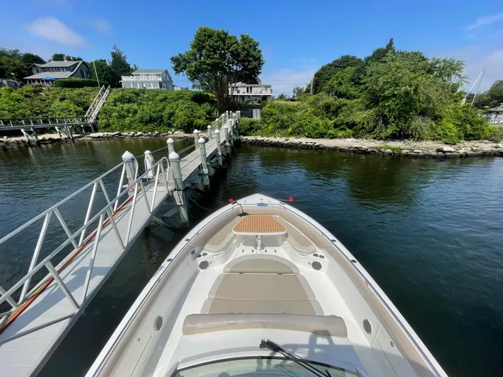  Yacht Photos Pics 2017 Boston Whaler 420 Outrage docked by a scenic waterfront with lush greenery.