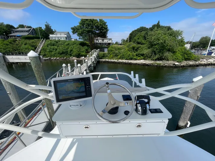  Yacht Photos Pics 2017 Boston Whaler 420 Outrage helm with navigation system, docked near lush greenery.