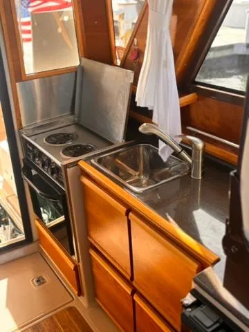 Seahorse Yacht Photos Pics 2016 Cutwater 28 LE boat kitchen with stove, sink, and wooden cabinetry.