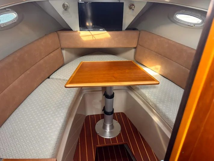 Seahorse Yacht Photos Pics 2016 Cutwater 28 LE cabin interior with wood table, cushioned seating, and mounted TV.