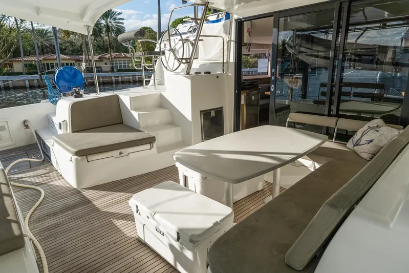 Benedetto Yacht Photos Pics 2020 Lagoon 42 yacht cockpit with seating, table, and helm station, docked by waterfront homes.