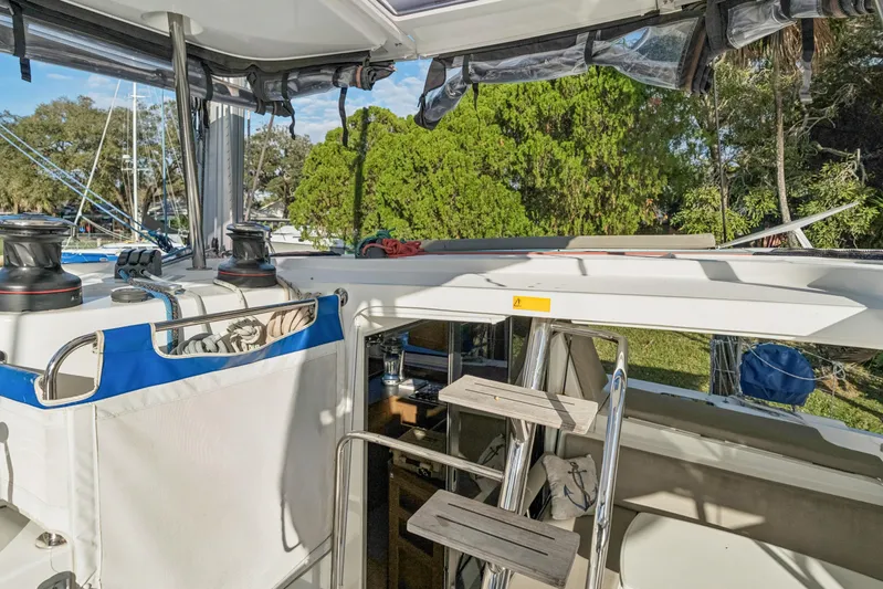Benedetto Yacht Photos Pics 2020 Lagoon 42 yacht cockpit with winches and ladder, surrounded by lush greenery.