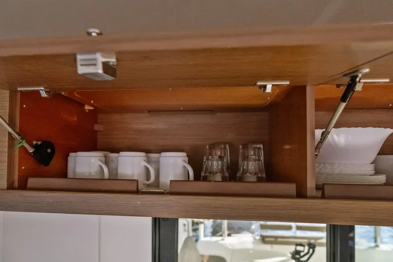 Benedetto Yacht Photos Pics Open cabinet in Lagoon 42 yacht with mugs, glasses, and plates neatly arranged.