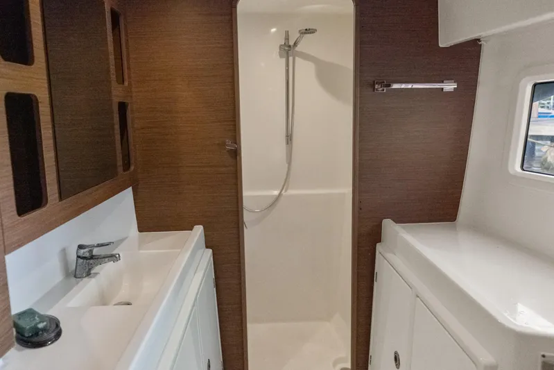 Benedetto Yacht Photos Pics 2020 Lagoon 42 yacht bathroom with modern shower, sink, and wooden cabinetry.