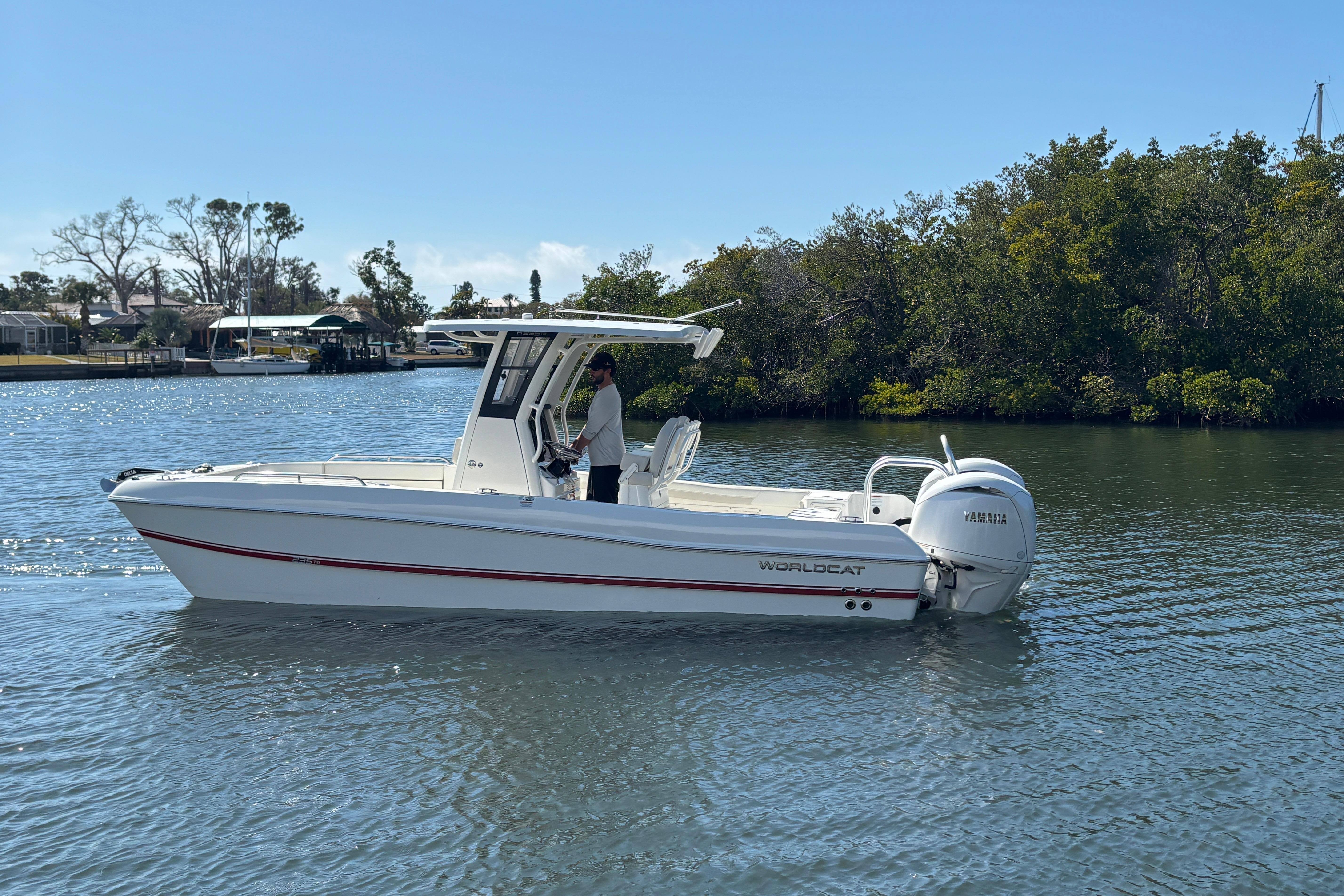 2026 World Cat 235 TE boat cruising on a calm river with lush greenery.