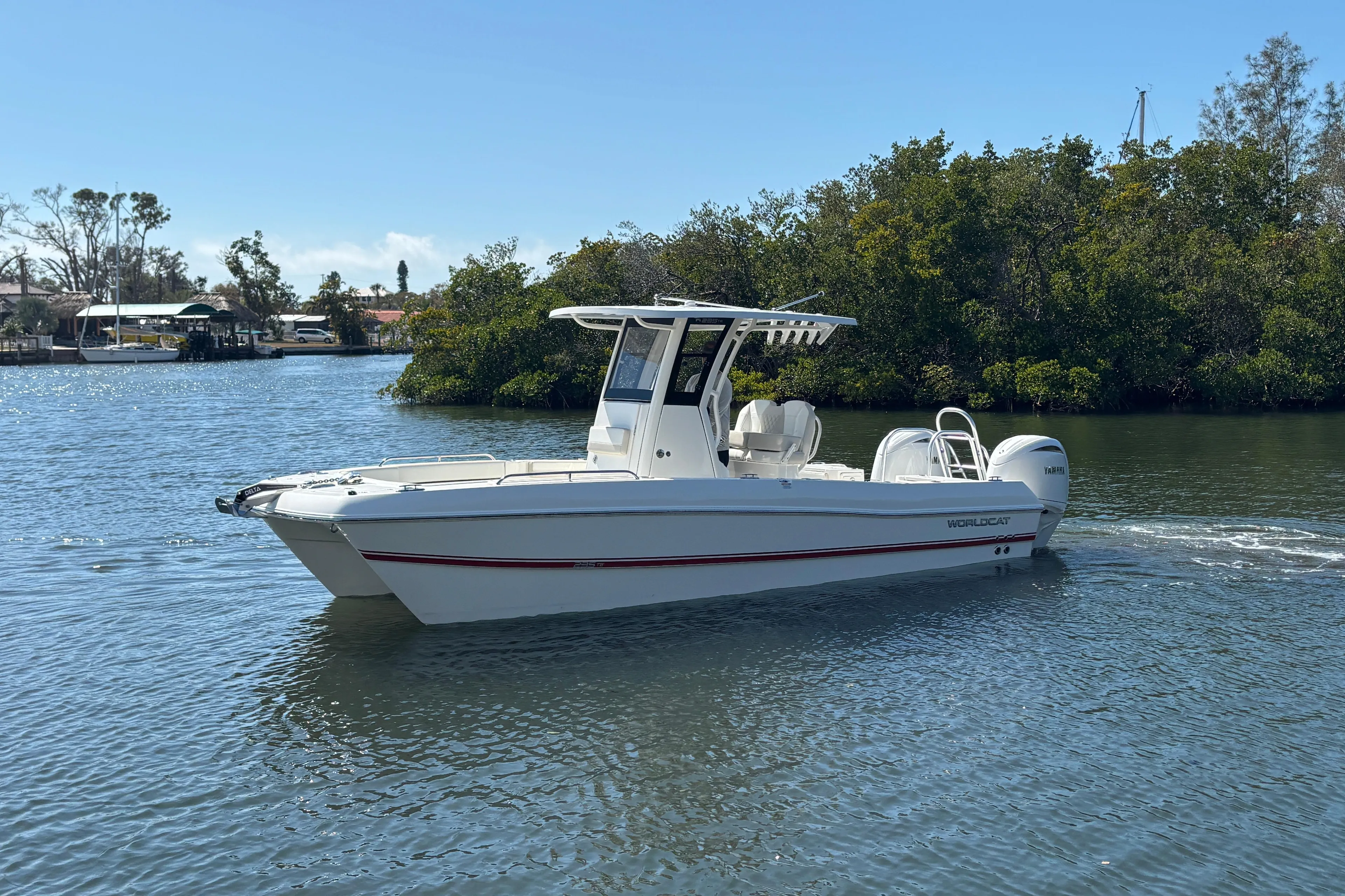 2026 World Cat 235 TE boat cruising on a calm river with lush greenery.
