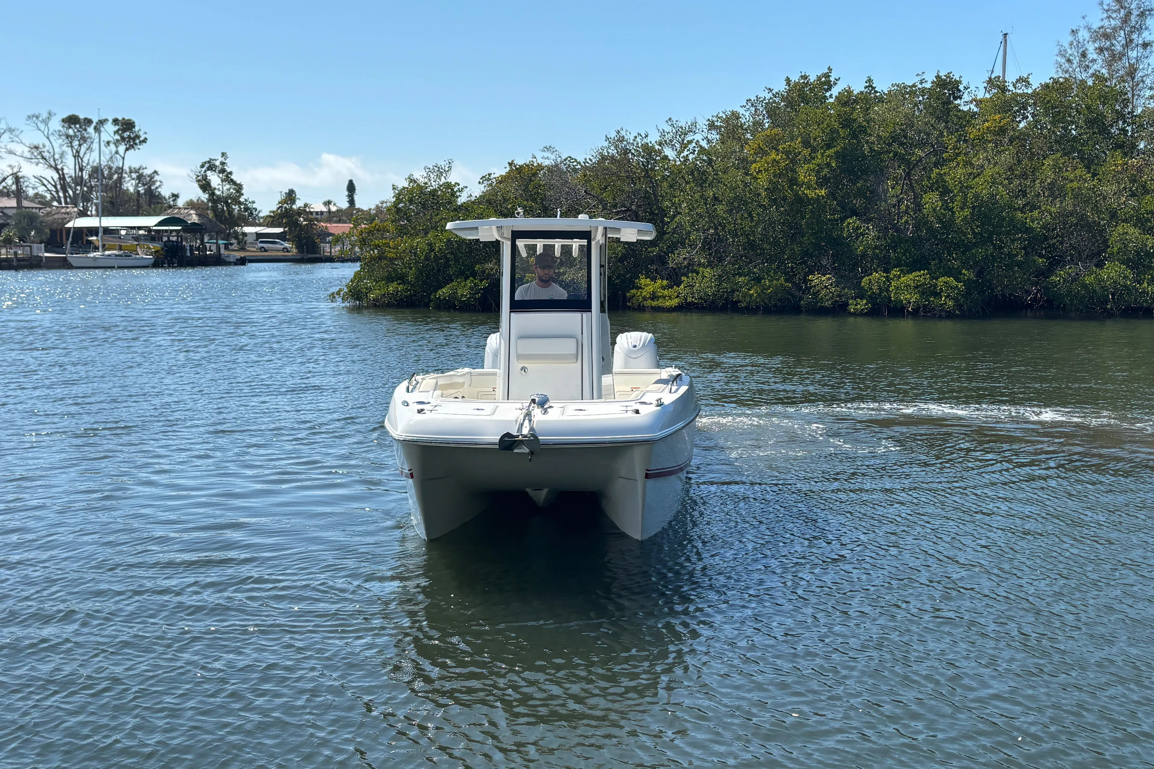 2026 World Cat 235 TE boat navigating a calm waterway surrounded by lush greenery.
