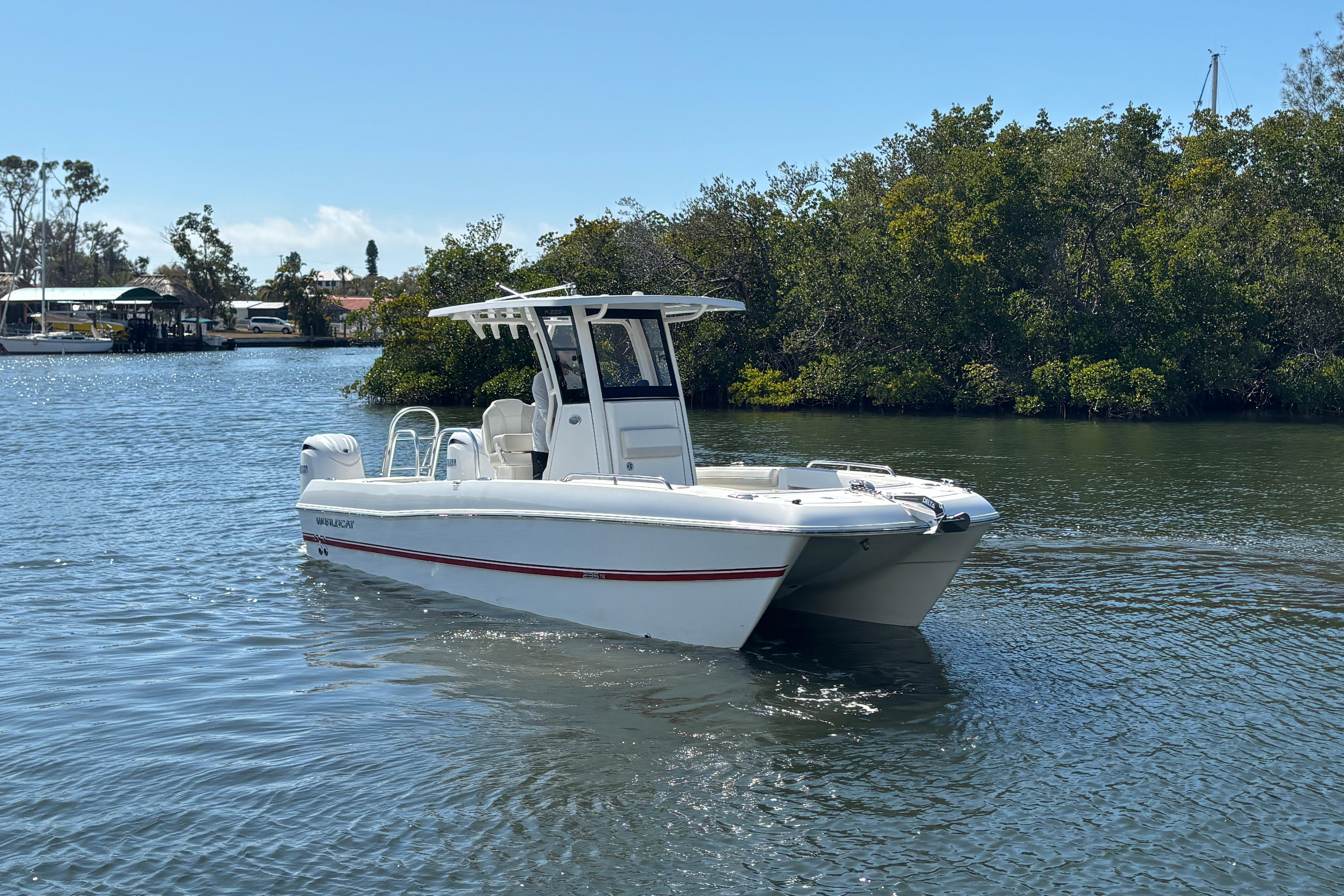 2026 World Cat 235 TE boat on calm water near lush greenery.