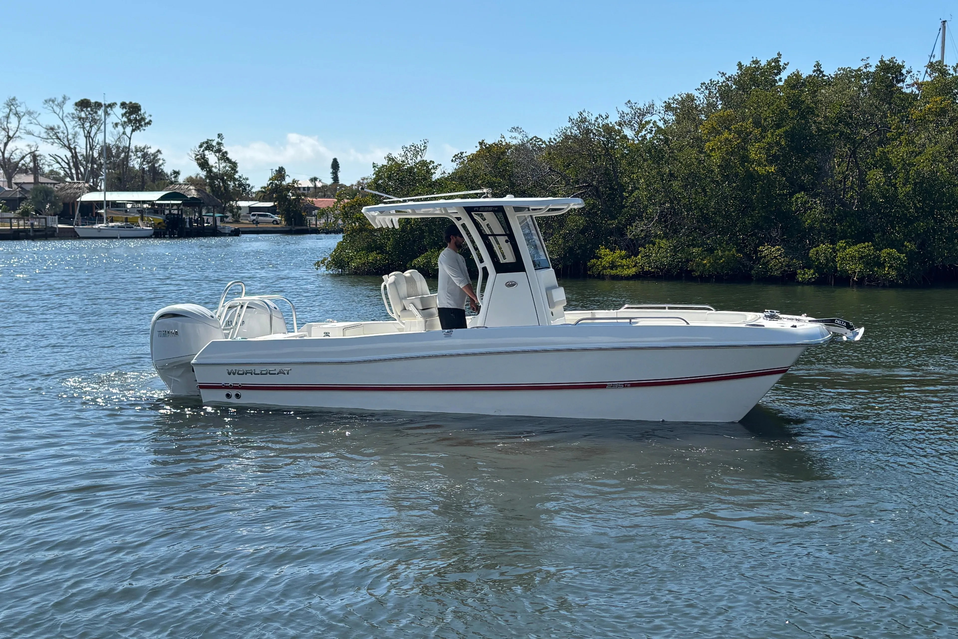 2026 World Cat 235 TE boat cruising on a calm river with lush greenery.