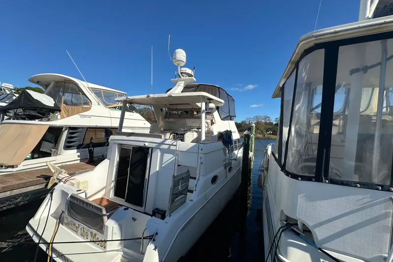  Yacht Photos Pics 1999 Silverton 442 Cockpit Motor Yacht docked between other boats under clear blue sky.