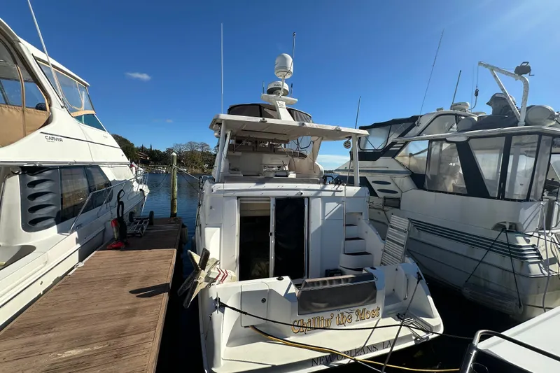  Yacht Photos Pics 1999 Silverton 442 Cockpit Motor Yacht docked between boats on a sunny day.