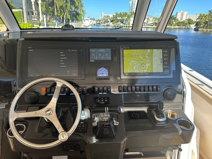 Leap Year Yacht Photos Pics 2018 Pursuit 408S boat helm with navigation screens and steering wheel, overlooking a scenic waterway.