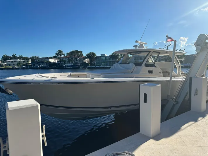 Leap Year Yacht Photos Pics 2018 Pursuit 408S boat docked by waterfront homes under clear blue sky.