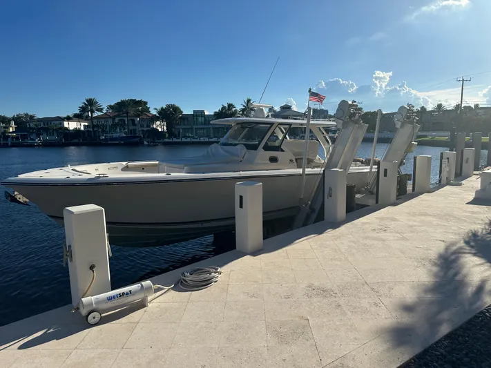 Leap Year Yacht Photos Pics 2018 Pursuit 408S boat docked by waterfront homes under clear sky.