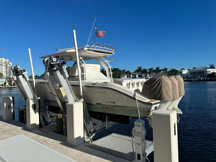 Leap Year Yacht Photos Pics 2018 Pursuit 408S boat docked on lift, American flag, waterfront homes in background.