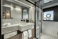 Luxurious yacht bathroom with marble sink, glass shower, and sea view window, Custom Line 37, 2022.