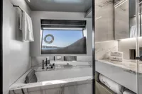 Luxurious yacht bathroom with marble finishes, modern fixtures, and ocean view window. Custom Line 37, 2022.