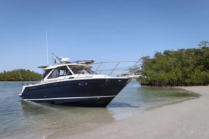  Yacht Photos Pics 2026 Cutwater C-248 Coupe boat anchored on a sandy beach with clear blue sky.