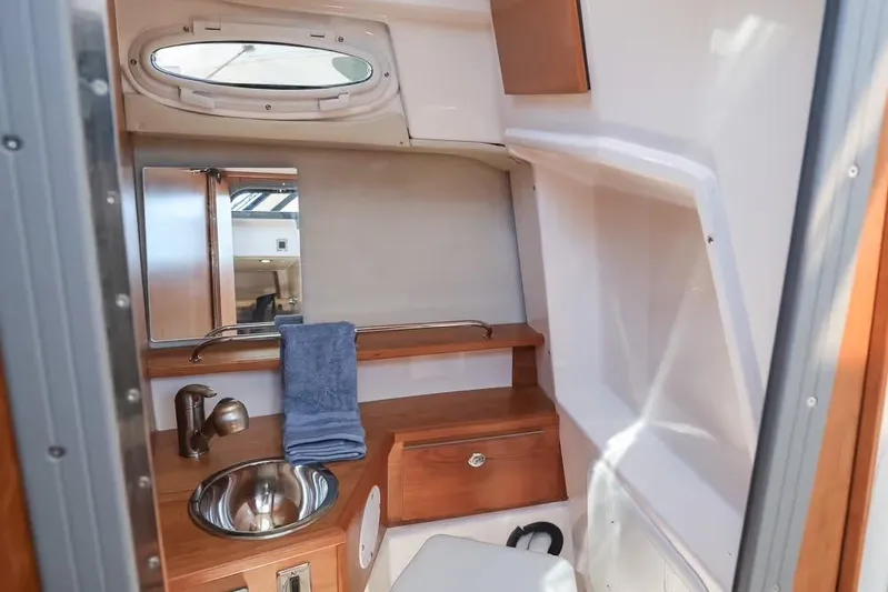  Yacht Photos Pics 2026 Cutwater C-248 Coupe interior bathroom with sink, mirror, and wooden cabinetry.