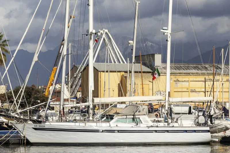  Yacht Photos Pics 1982 Benetti Sail Division 16m Motorsailer docked at a marina with mountains in the background.
