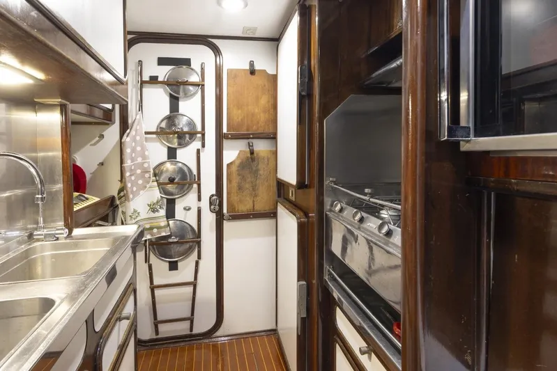  Yacht Photos Pics 1982 Benetti Sail Division 16m Motorsailer kitchen with stainless steel sink and wooden cabinetry.