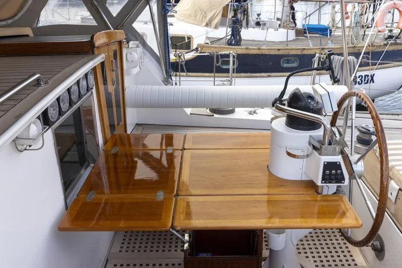  Yacht Photos Pics 1982 Benetti Sail Division 16m Motorsailer cockpit with wooden table and steering wheel.