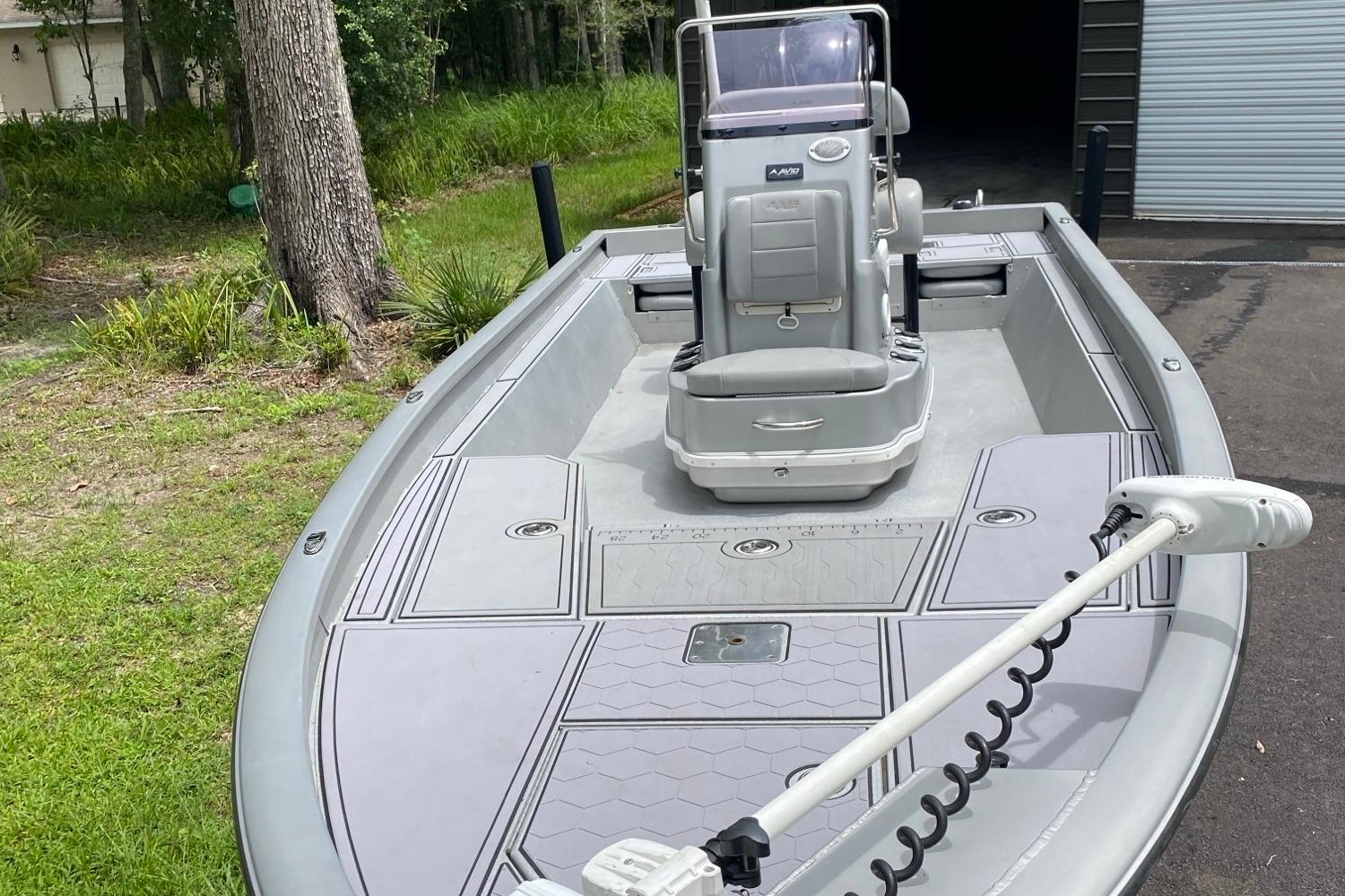 2021 Avid 23 FS Magnum boat with sleek design, parked outdoors near greenery.