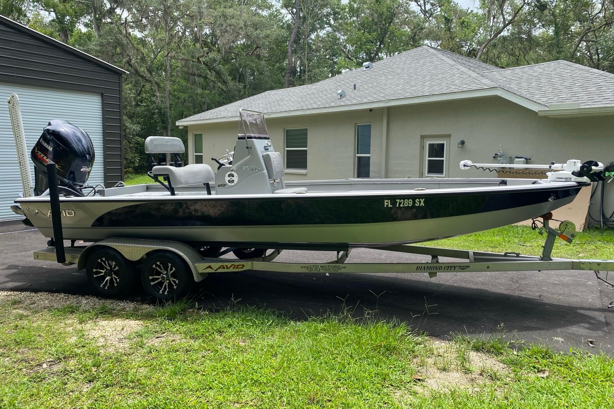 2021 Avid 23 FS Magnum boat on trailer, parked beside a house.