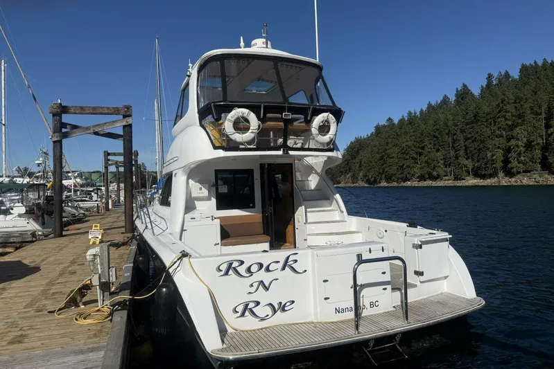  Yacht Photos Pics Royal Pacific 476 Sport Cruiser 2000 docked at marina, sunny day, forested background.