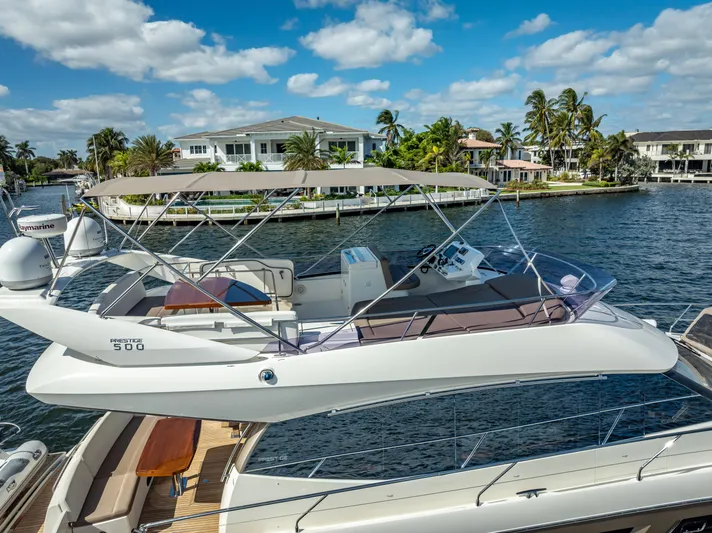 Miss Zoe Yacht Photos Pics 2014 Prestige 500 Fly yacht docked by waterfront homes under a blue sky.