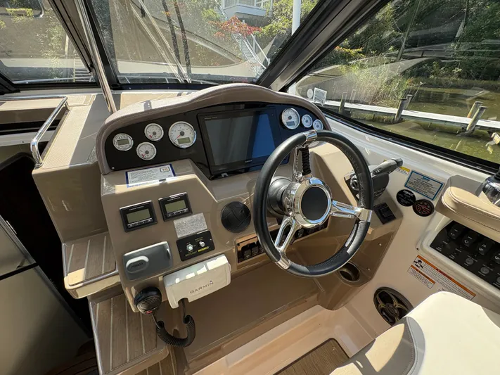 Wining Down Yacht Photos Pics 2016 Regal 35 Sport Coupe helm with steering wheel, gauges, and navigation controls.