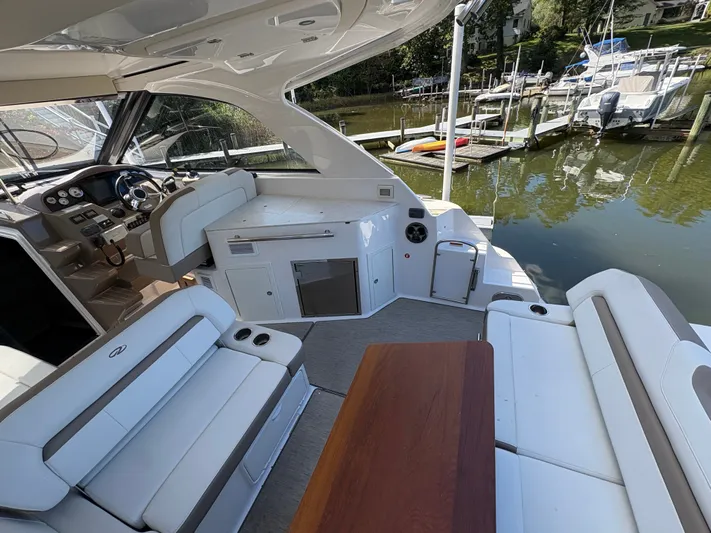 Wining Down Yacht Photos Pics Interior of 2016 Regal 35 Sport Coupe yacht with seating and helm, docked by water.