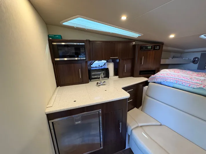 Wining Down Yacht Photos Pics 2016 Regal 35 Sport Coupe interior with kitchenette, microwave, and seating area.
