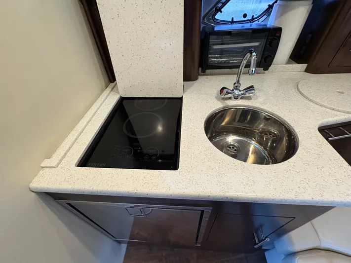 Wining Down Yacht Photos Pics 2016 Regal 35 Sport Coupe kitchen with induction cooktop and stainless steel sink.