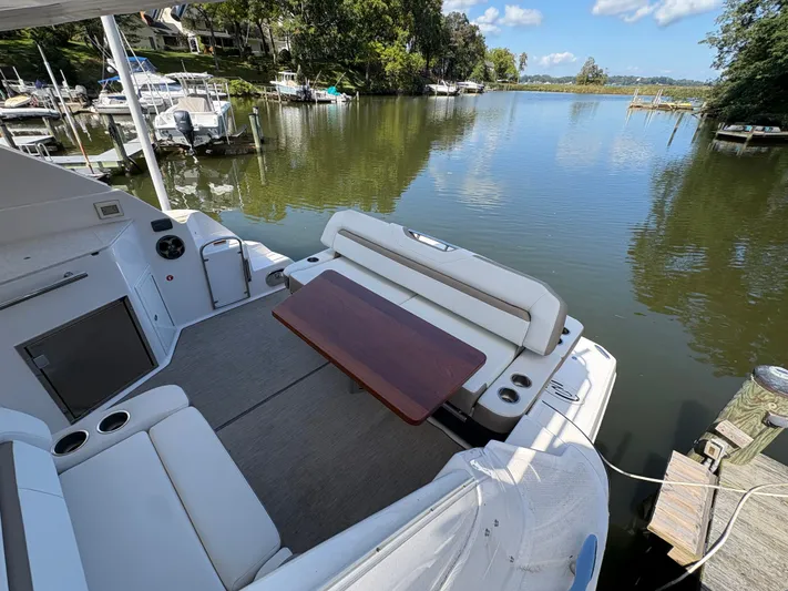 Wining Down Yacht Photos Pics 2016 Regal 35 Sport Coupe boat interior with seating and table, docked by a scenic lake.