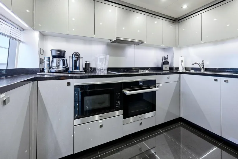 Pura Vida Yacht Photos Pics Modern kitchen in 2022 Sunseeker Motoryacht with sleek appliances and glossy cabinetry.