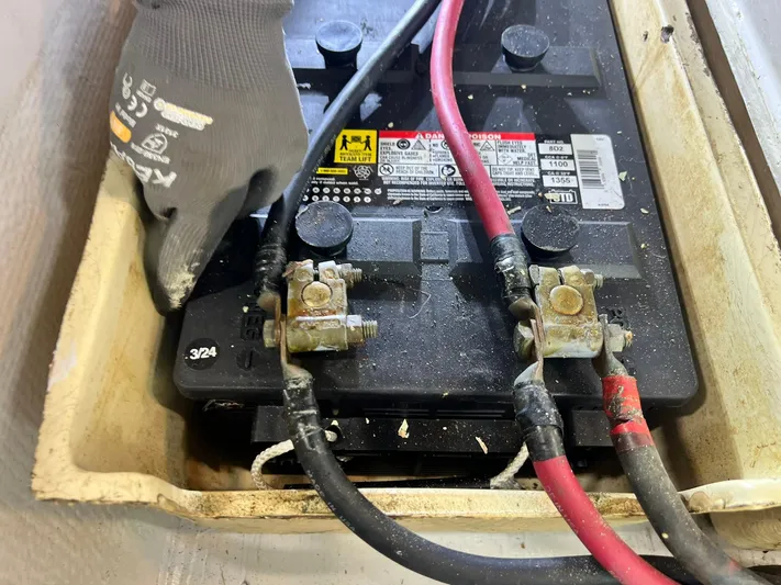 Arvo Arrow Yacht Photos Pics Battery maintenance on 1985 Chris-Craft 460 Constellation with connected cables and gloved hand.