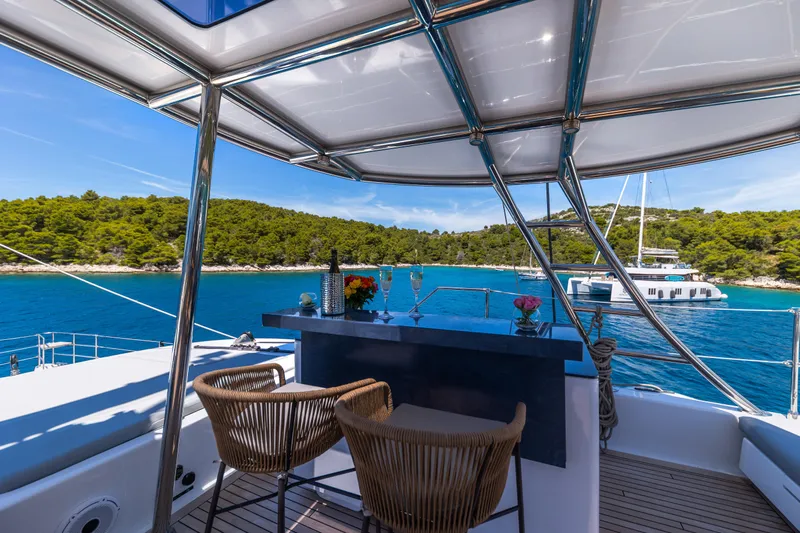 Mr.si Yacht Photos Pics Luxurious Sunreef 60 Sailing yacht interior with bar, overlooking serene blue waters and lush greenery.