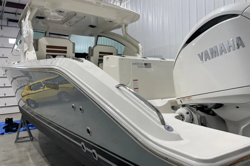  Yacht Photos Pics 2024 Pursuit DC 326 Dual Console boat with Yamaha engine in a garage setting.