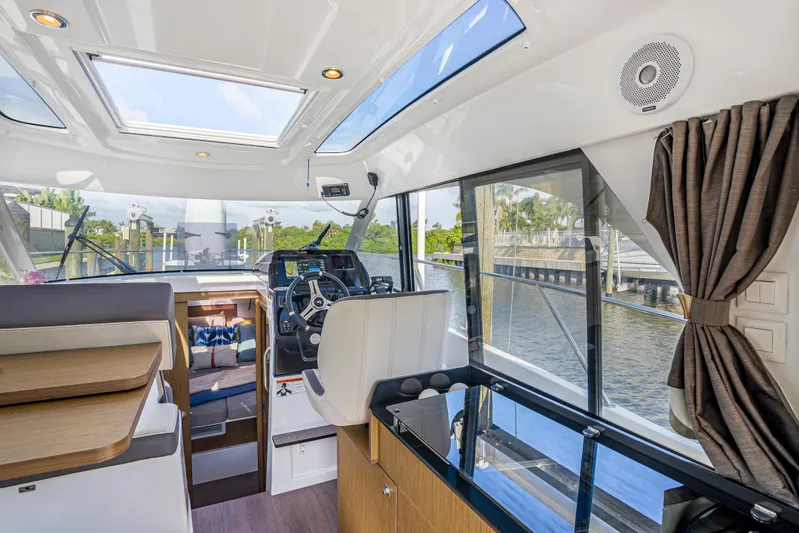  Yacht Photos Pics Interior of 2021 Beneteau Antares 9 boat, featuring helm, seating, and panoramic windows.