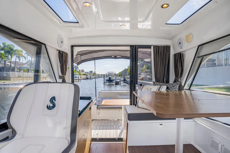  Yacht Photos Pics Interior of 2021 Beneteau Antares 9, featuring seating and table, with waterfront view.