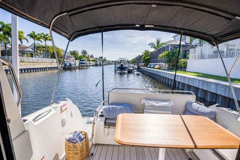 Yacht Photos Pics Beneteau Antares 9 (2021) boat interior with table, cushions, and canal view.