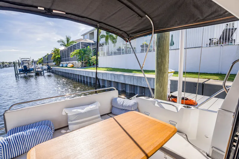  Yacht Photos Pics Cozy seating area on 2021 Beneteau Antares 9 boat, docked by a sunny waterfront.