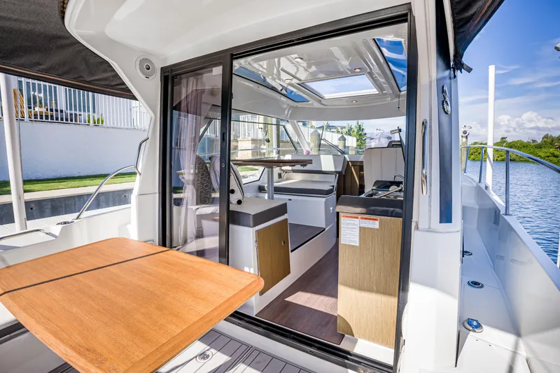  Yacht Photos Pics 2021 Beneteau Antares 9 interior view with open sliding door and wooden table.