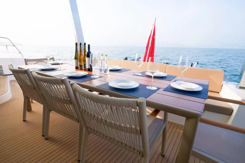  Yacht Photos Pics Luxury dining setup on 2025 Mazarin 55 Catamaran, ocean view, elegant tableware, and wine bottles.