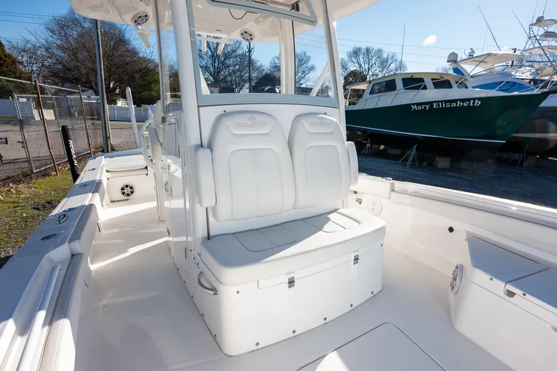 Our Trade Yacht Photos Pics 2024 Regulator 26XO boat interior with white seating and console, docked near other boats.