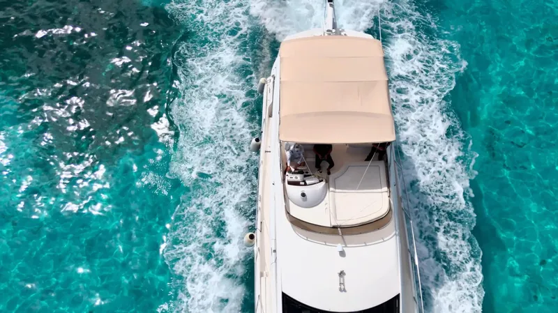 Itaca Yacht Photos Pics Aerial view of 2008 Sunseeker Manhattan 60 yacht cruising in clear turquoise waters.