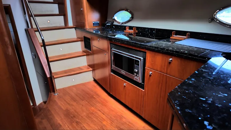 Itaca Yacht Photos Pics Luxurious kitchen interior of 2008 Sunseeker Manhattan 60 yacht with wooden cabinetry and black countertops.