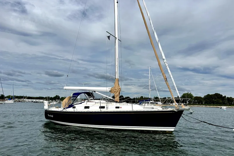 Blue Aweigh Yacht Photos Pics 2021 Tartan 345 sailboat anchored on calm water under a cloudy sky.