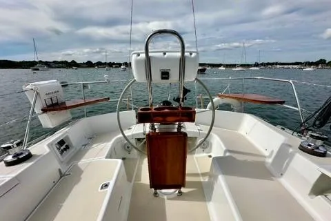 Blue Aweigh Yacht Photos Pics 2021 Tartan 345 sailboat cockpit with steering wheel, wooden accents, and scenic harbor view.